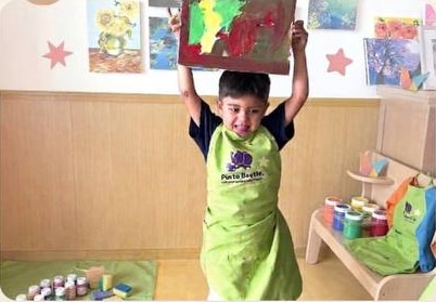 Child smiling with a finished painting at Pinto Beetle