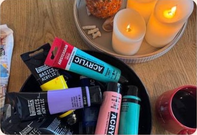 Paint tubes, candles, pineapple, and wine ready for a creative class