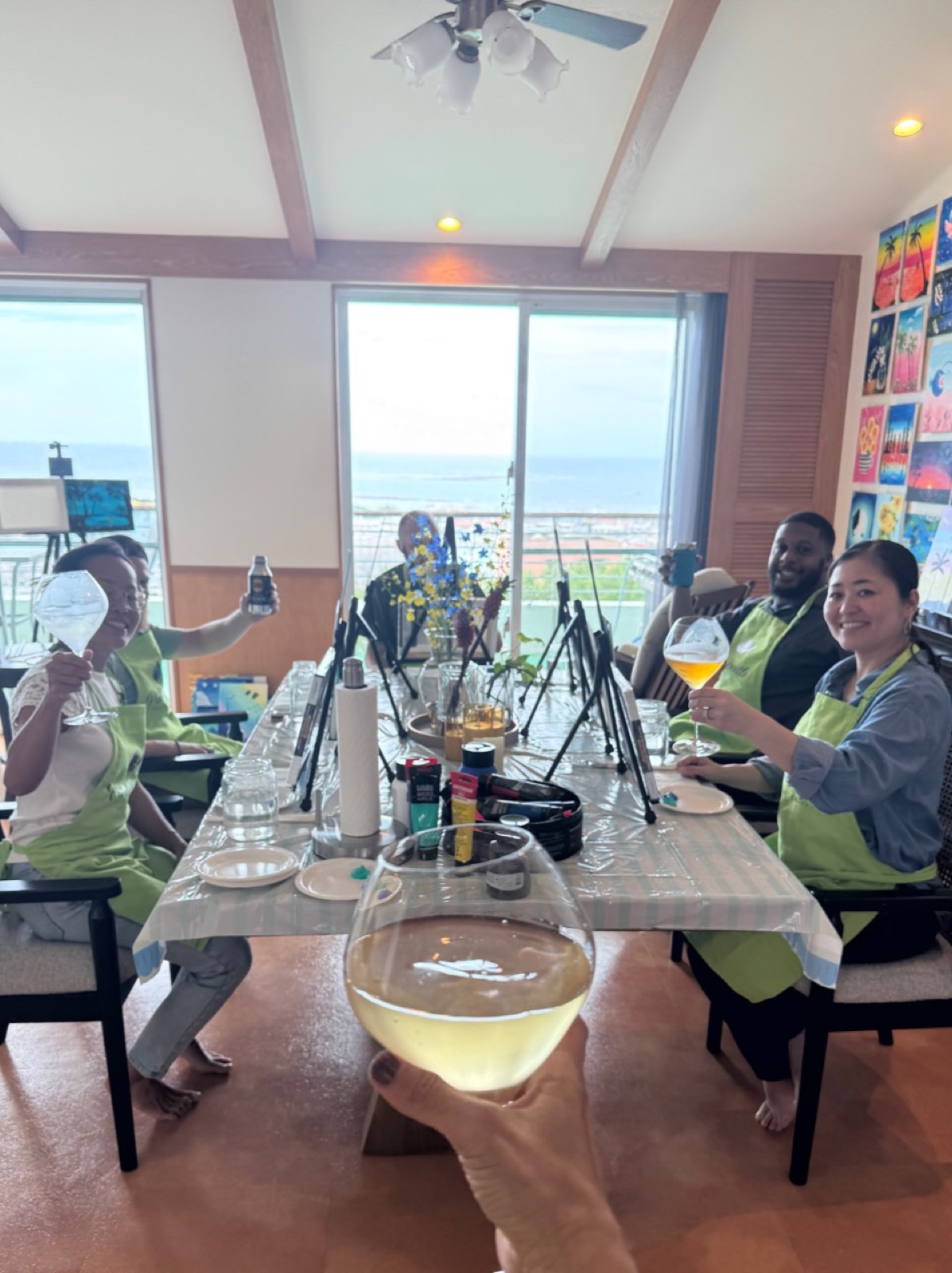 Pinto Beetle private session guests raising glasses around the painting table