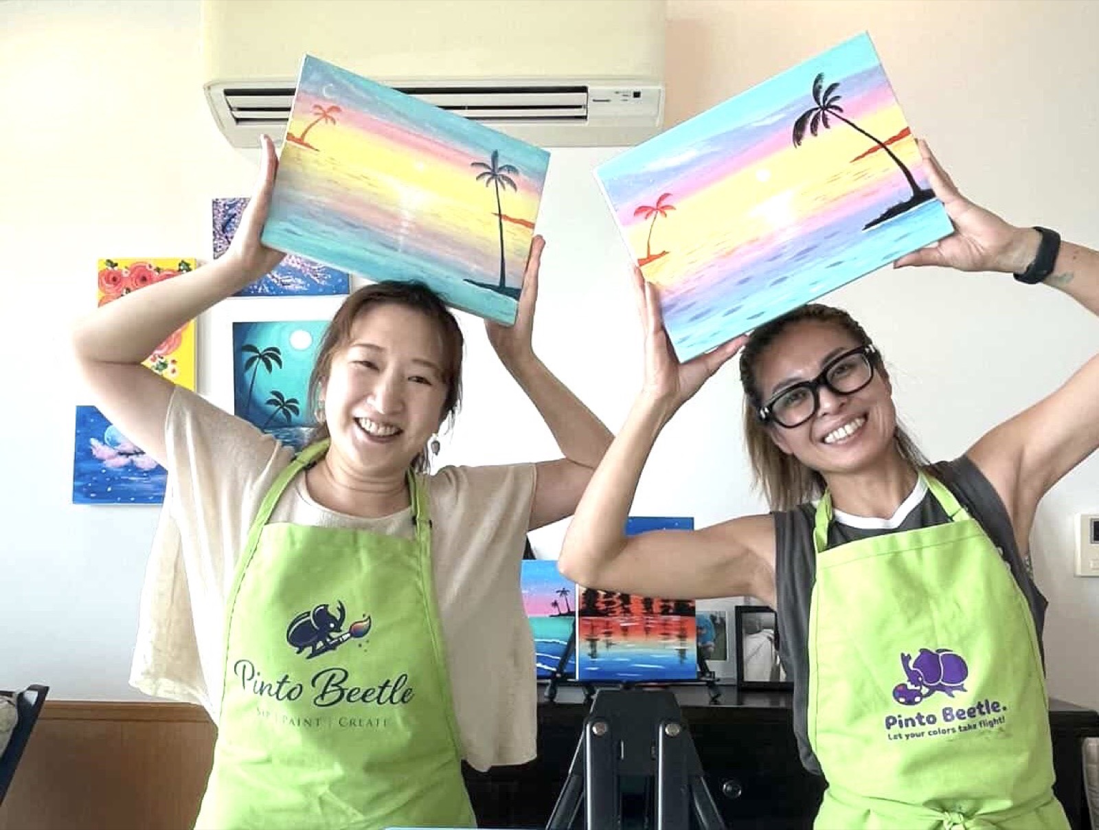 Two Pinto Beetle guests smiling with their finished pastel sunset paintings