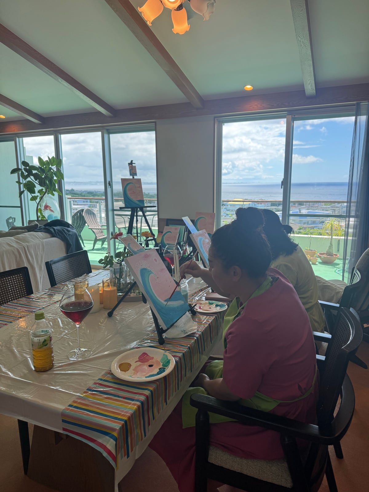 Pinto Beetle guest painting a pink moon wave canvas in the ocean-view studio