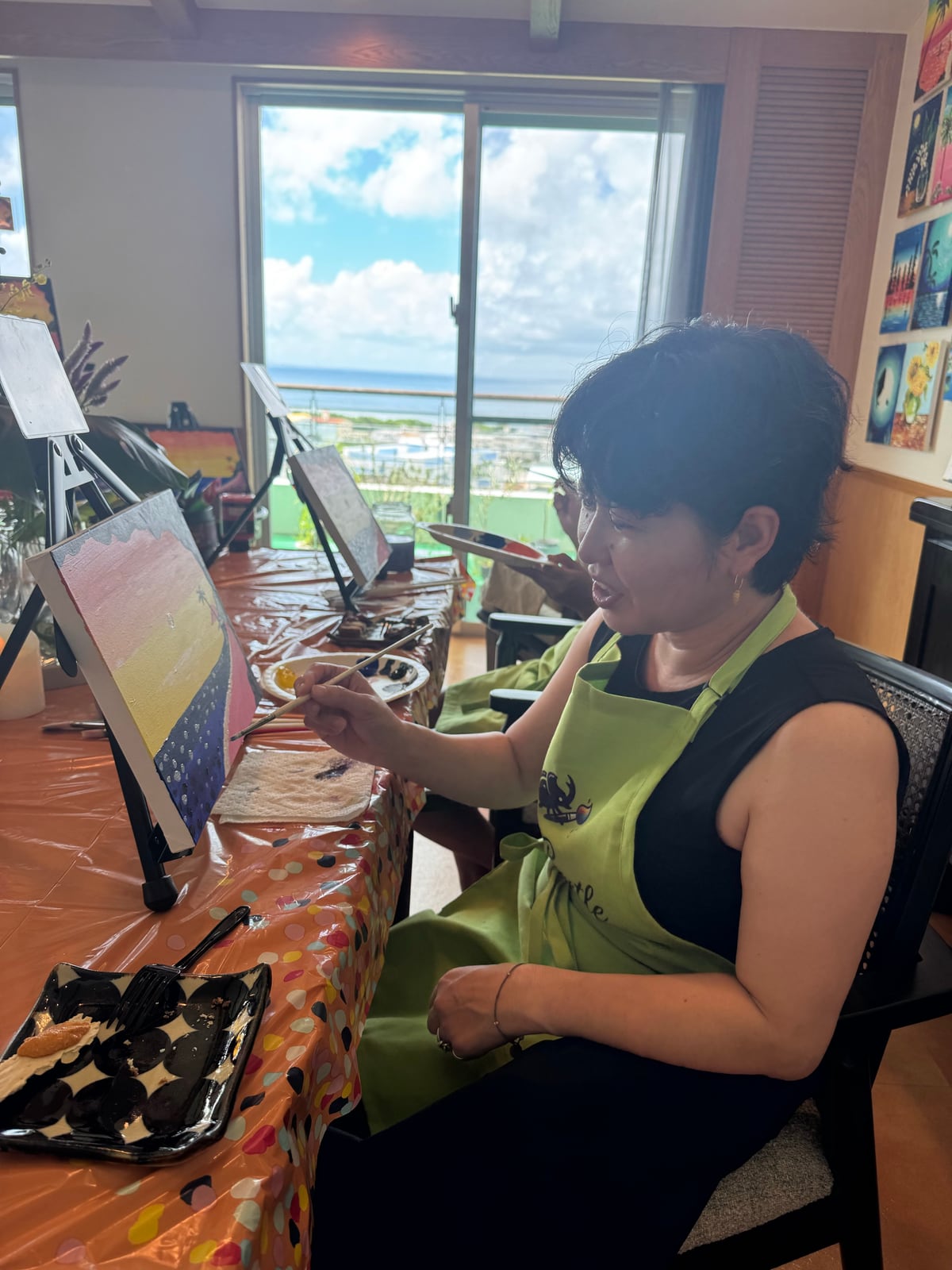 Pinto Beetle guest painting a sunset canvas beside the ocean-view window