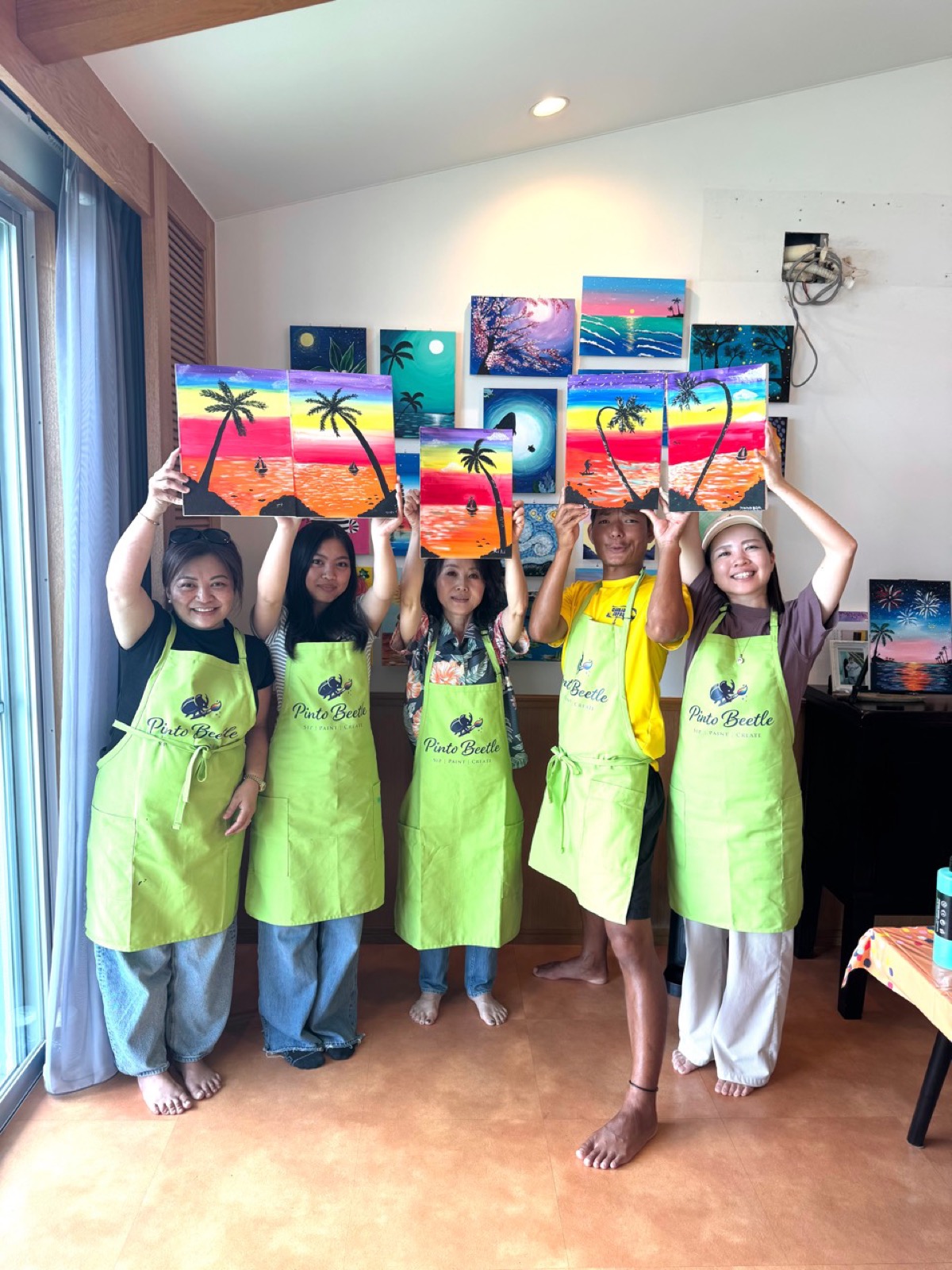 Pinto Beetle class guests holding their finished sunset paintings