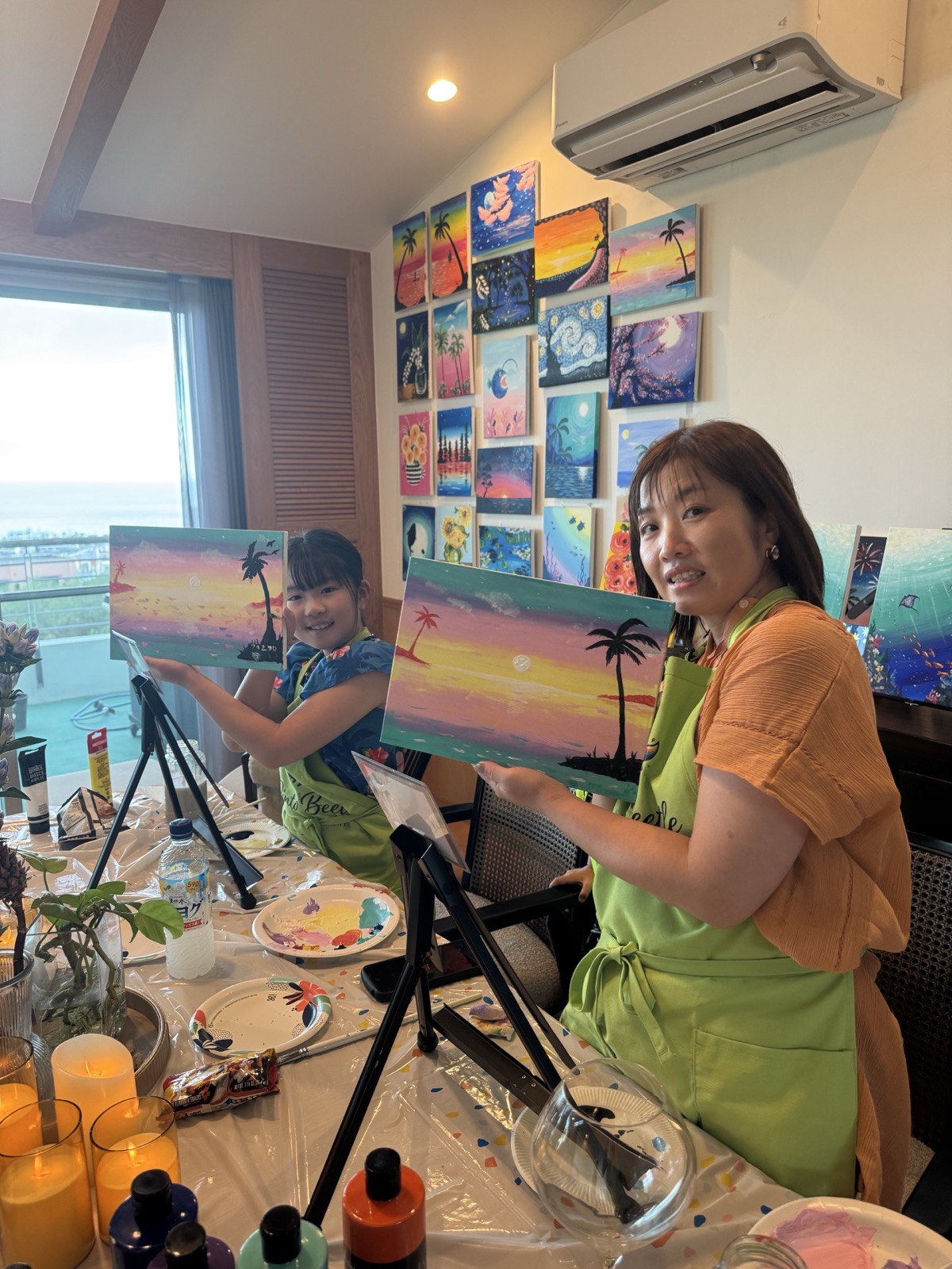 Pinto Beetle guests holding finished Sunset Paradise paintings in the studio
