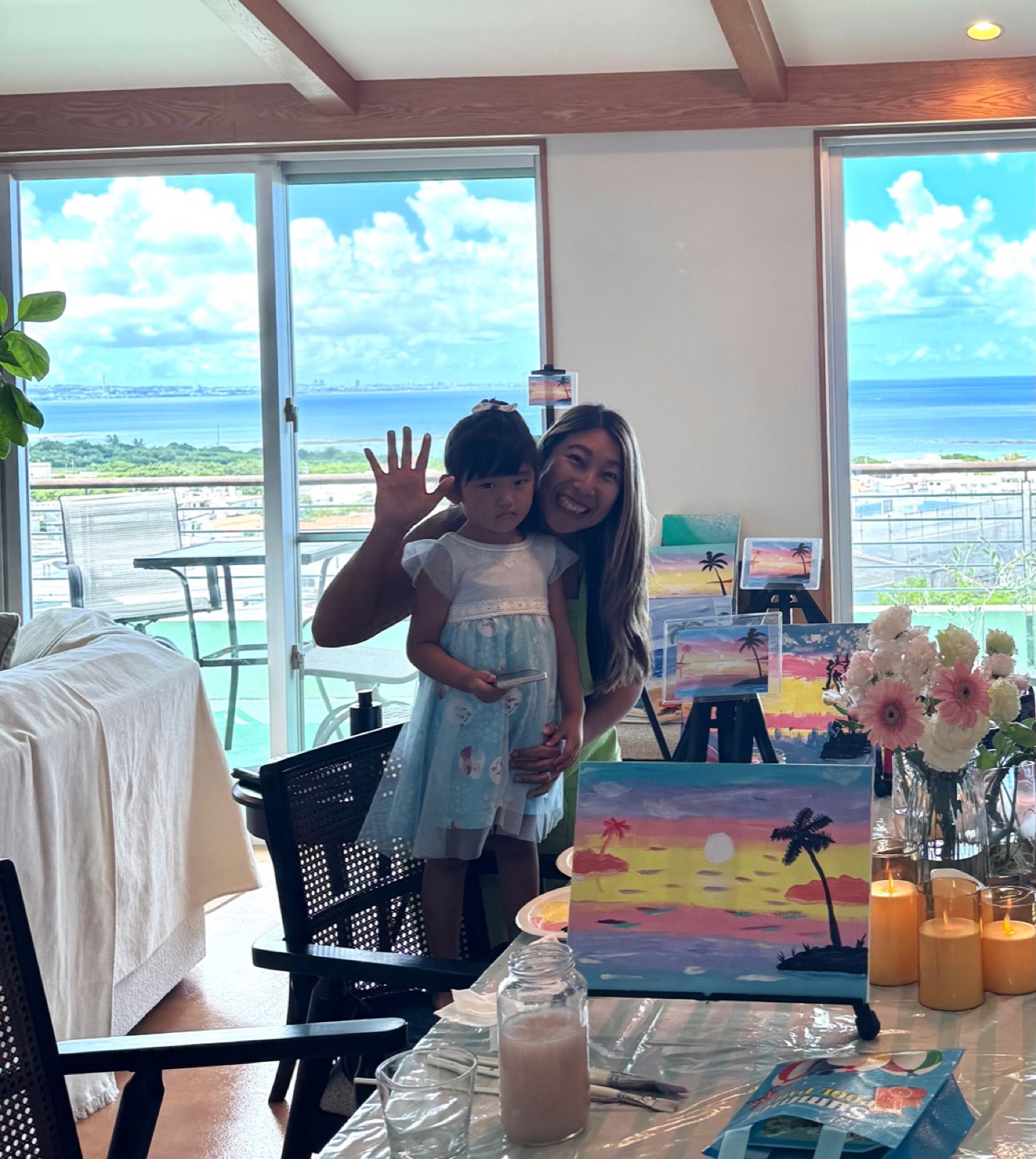 Pinto Beetle guest and child smiling in the ocean-view studio with sunset paintings