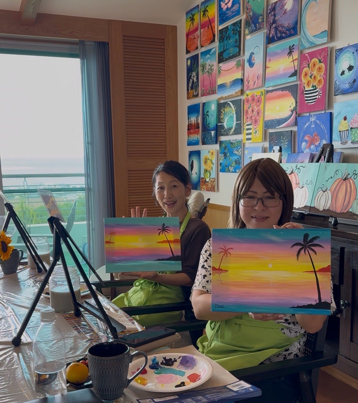 Two Pinto Beetle guests smiling with their finished tropical sunset paintings