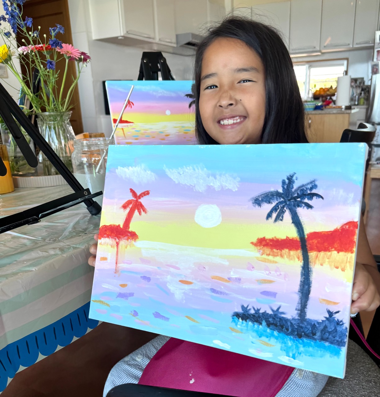 Young Pinto Beetle guest smiling with her finished tropical sunset painting